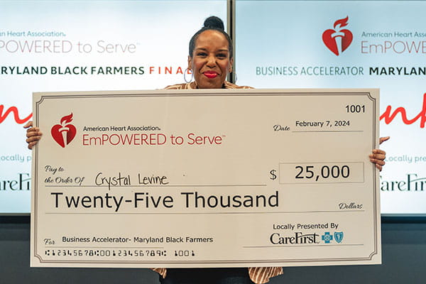 Crystal Levine is holding a big check from the American Heart Association showing her 2nd place win at the ETS Maryland Black Farmers Business Accelerator finale.