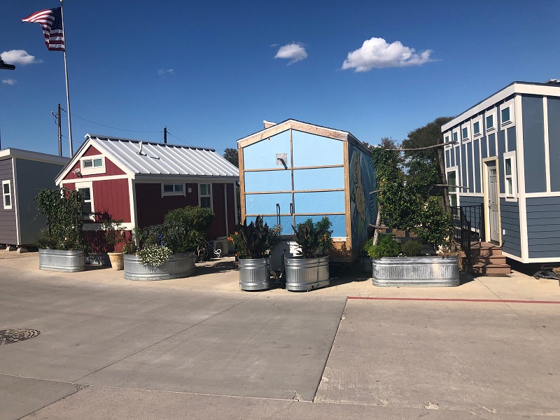 a row of maroon, light blue and dark blue tiny homes
