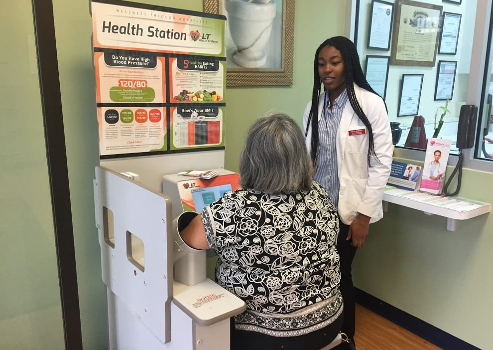 Jesse Hoe of the Student National Pharmaceutical Association (SNPhA) teaches a community member how to take her blood pressure
