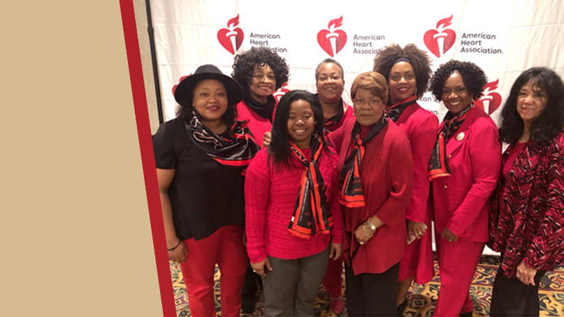 a group photo of Delta Sigma Theta members wearing red in front of an AHA step-and-repeat backdrop
