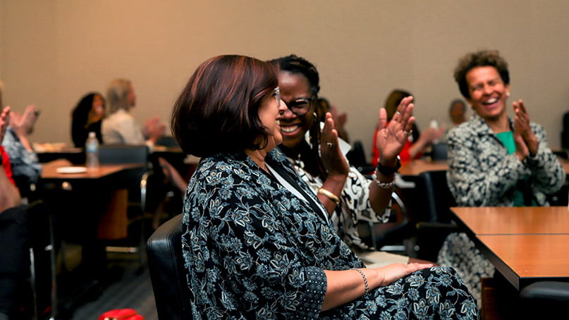 At the EmPOWERED to Serve Minnesota Business Accelerator 2022 finale, finalists are sitting around a table smiling and clapping.