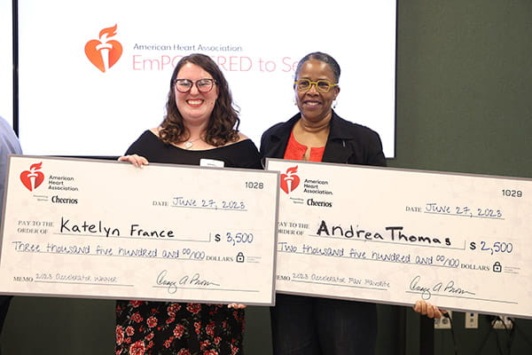 Katelyn France and Andrea Thomas posing with their big checks from the American Heart Association at the ETS Minnesota Business Accelerator finale awards ceremony