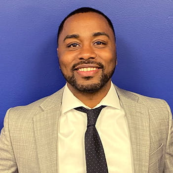 headshot of Luciano Sewell against a blue background