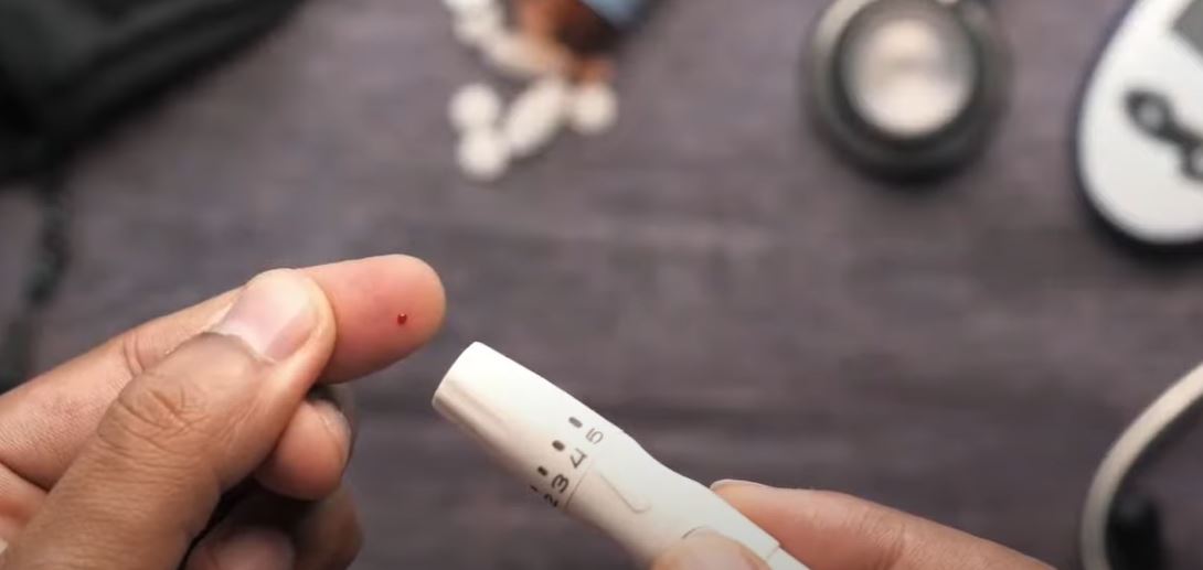 person pricking their finger to use a glucose testing machine