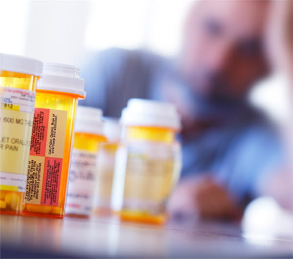 pill bottles on a table with a man out of focus in the background