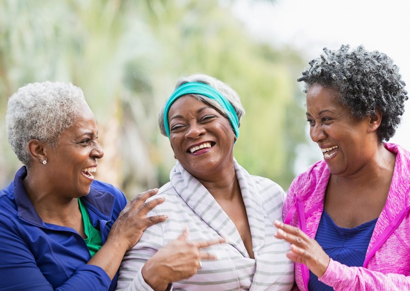 three senior Black women smiling and talking