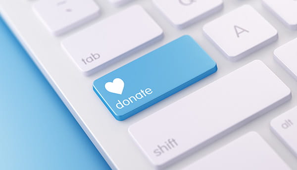 a cropped white computer keyboard with one blue key containing a white heart and the word donate a cropped white computer keyboard with one blue key containing a white heart and the word donate