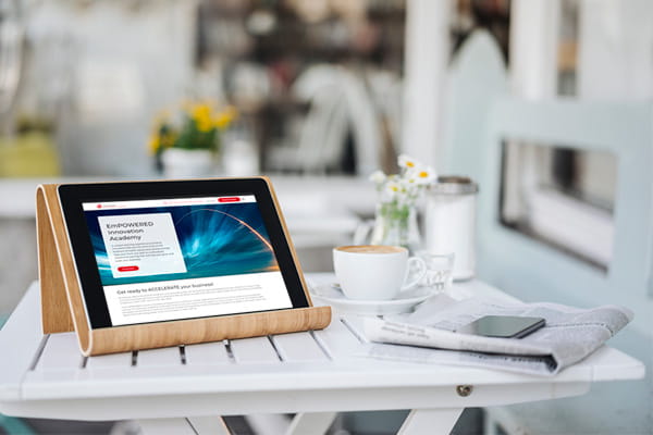 a digital tablet, newspaper, smartphone and coffee cup are sitting on a white table inside a bright living space