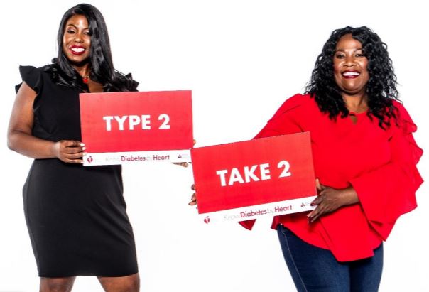 Two women holding Type 2 Take 2 signs