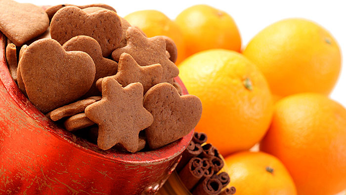 close up of gingerbread cookies, cinnamon sticks, and fresh oranges