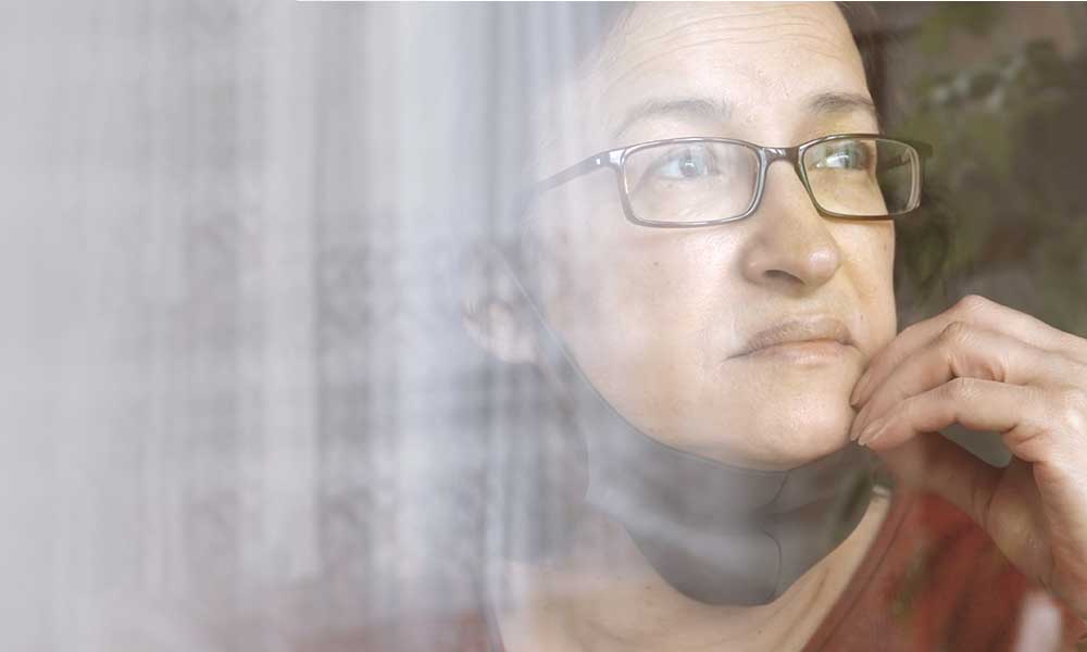 woman wearing protective mask looking out of window