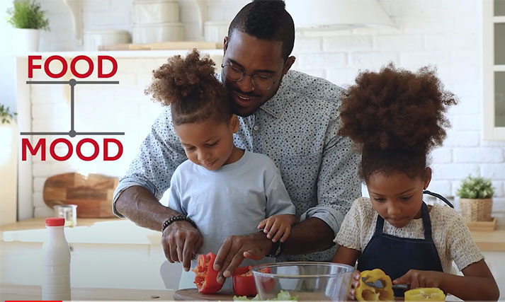 father and young daughters cook food to boost their mood