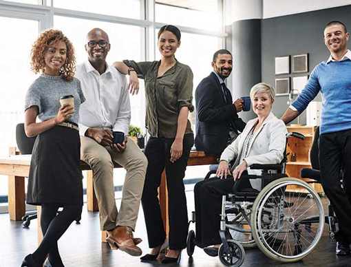 group of diverse people in a work environment posing for photo while smiling