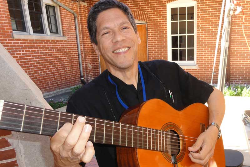 Frank playing his guitar and smiling