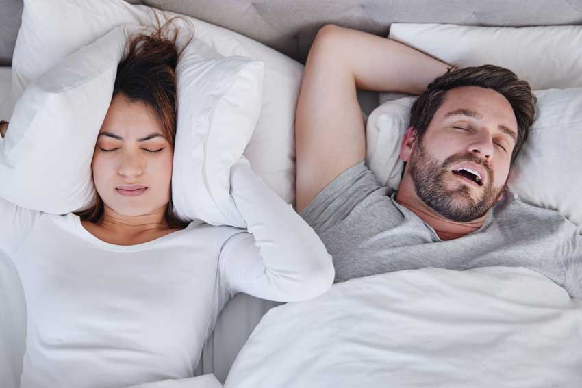 woman covering ears due to husband snoring