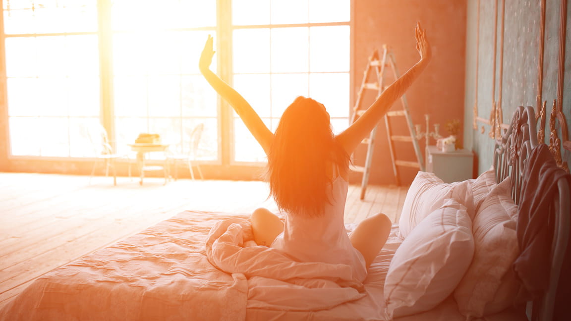 woman stretching out of bed at dawn
