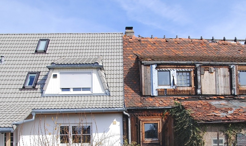 Two houses pictured side by side. The left house has nice paint and a new roof, and the right house has debris on the walls and a roof that is falling apart.