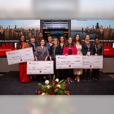 The 2026 EmPOWERED to Serve National Business Accelerator grant recipients are standing on a stage holding giant checks amongst American Heart Association representatives.