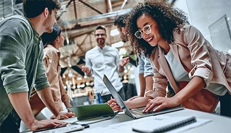 a group of diverse coworkers meeting in an office around a table of digital devices a group of diverse coworkers meeting in an office around a table of digital devices
