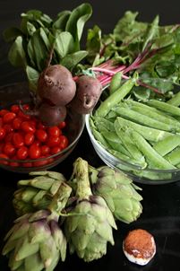 Fruits and vegetables in glass bowls and spread out on a surface.