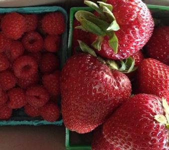 Raspberries and strawberries in blue and green cardboard containers