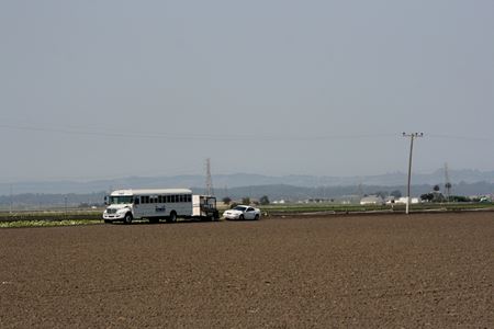 A field of farmland with vehicles in the background