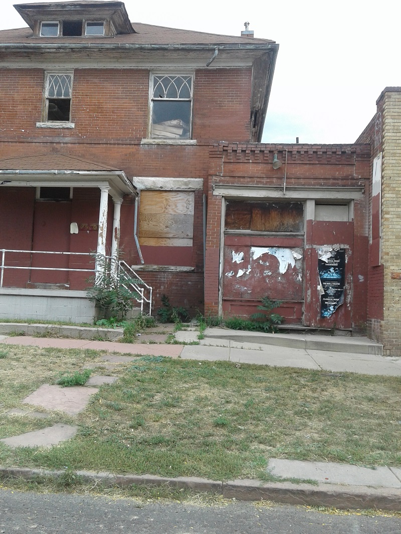 An older boarded up brick two-story structure in Denver, Colorado.